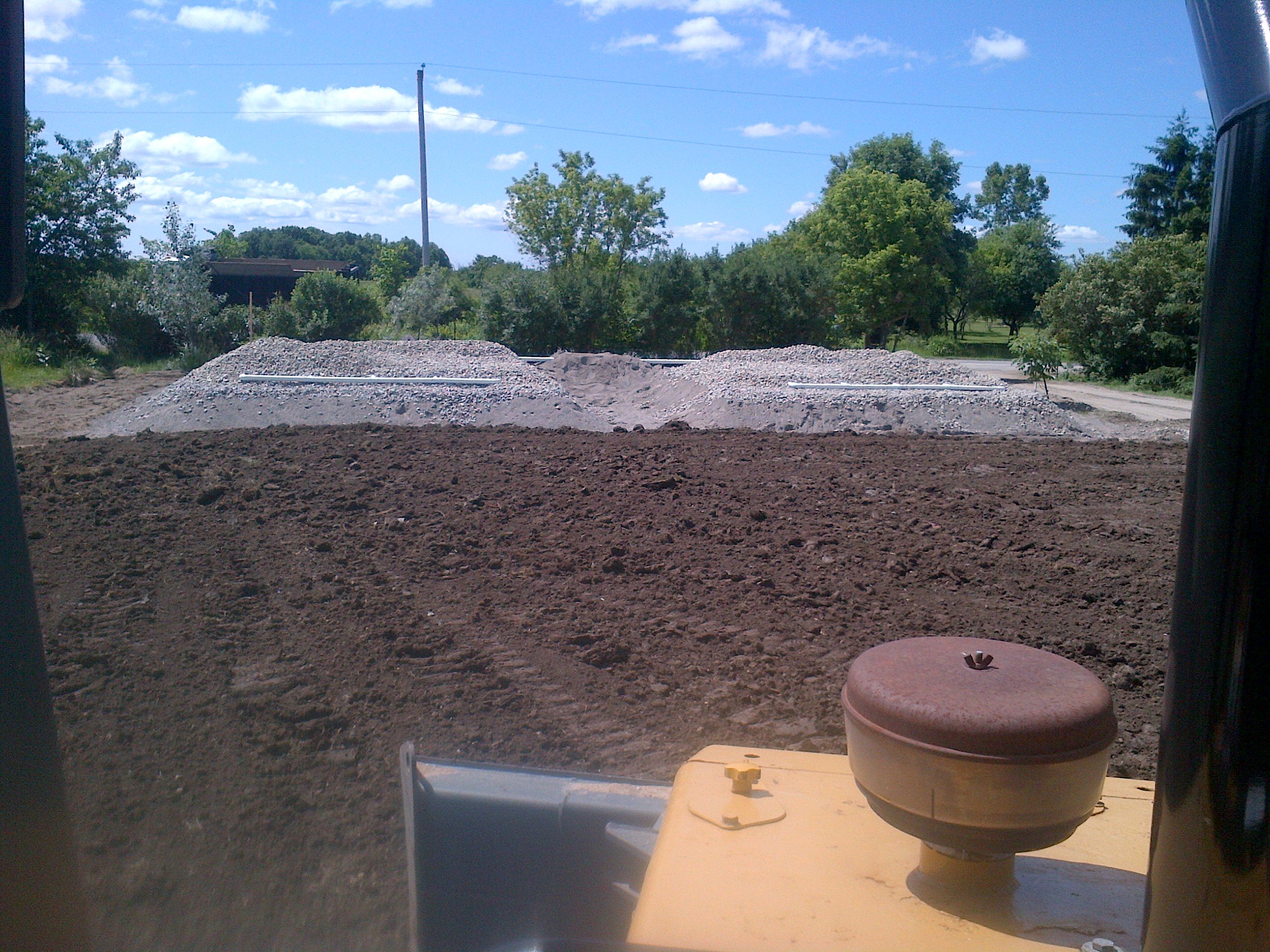 Trim dozer spreading topsoil over a filter bed septic system in Haldimand, Ontario