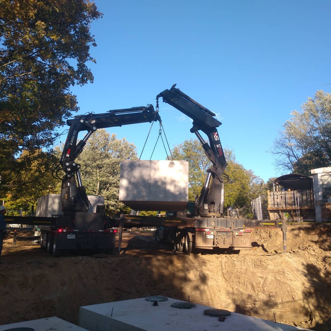 Two cranes working together to deliver and position a commercial septic tank in Haldimand.