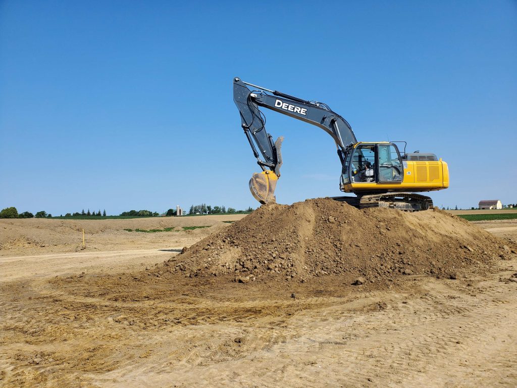 Excavator loading topsoil during road and earthworks construction