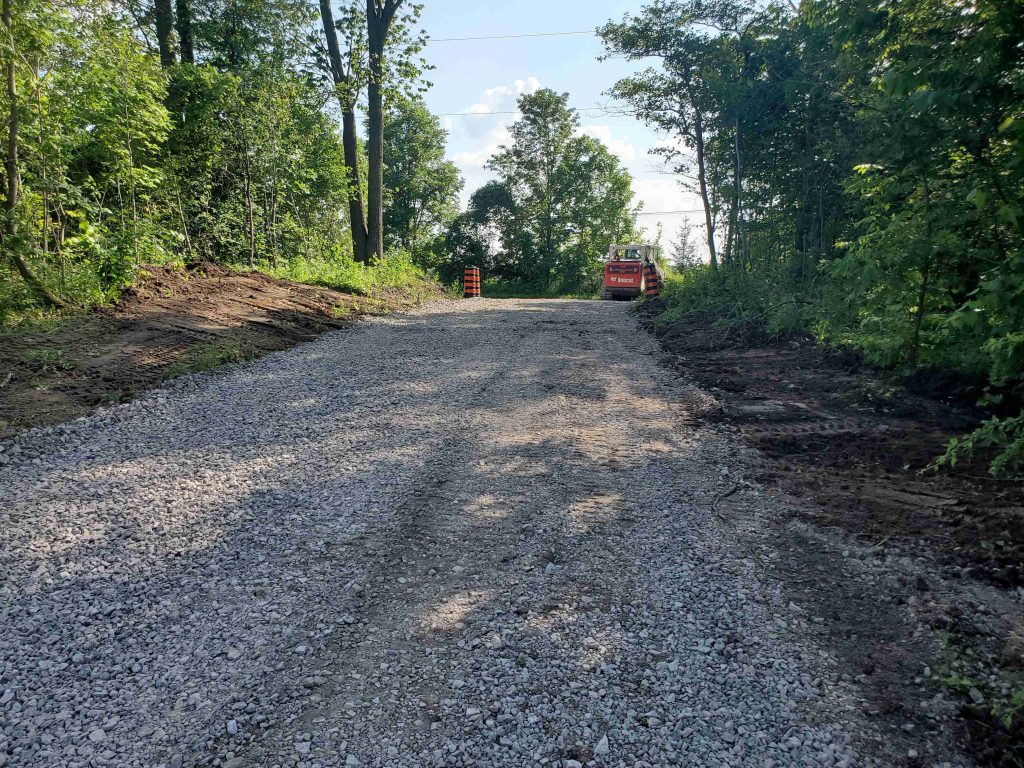 Completed gravel access road through a wooded property