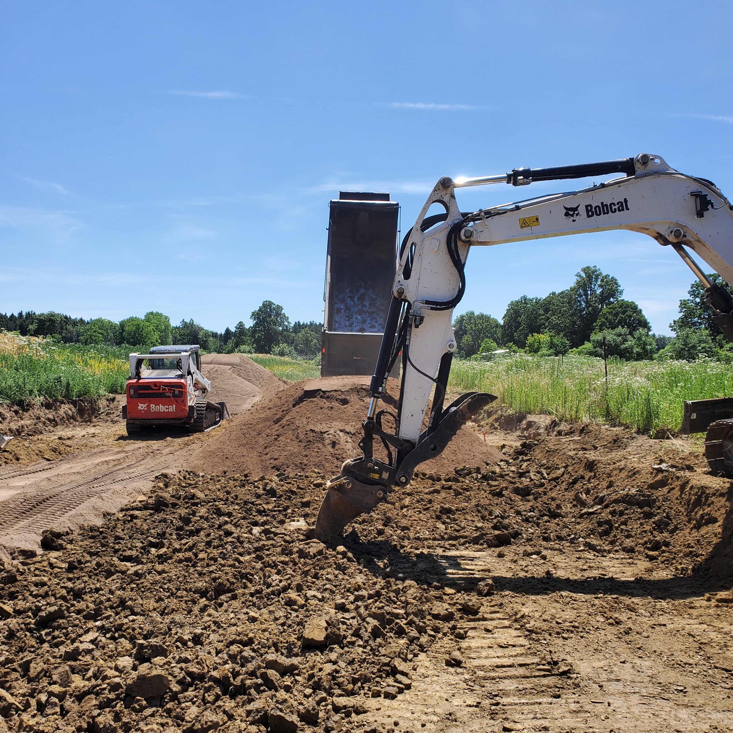 Alpha Ex team scarifying clay subsoil and placing sand for sand mound septic system in Hamilton