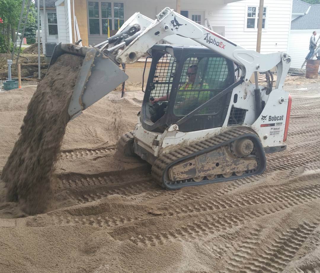 Septic sand being placed with light track-mounted equipment operated by a skilled operator for proper leaching bed construction.