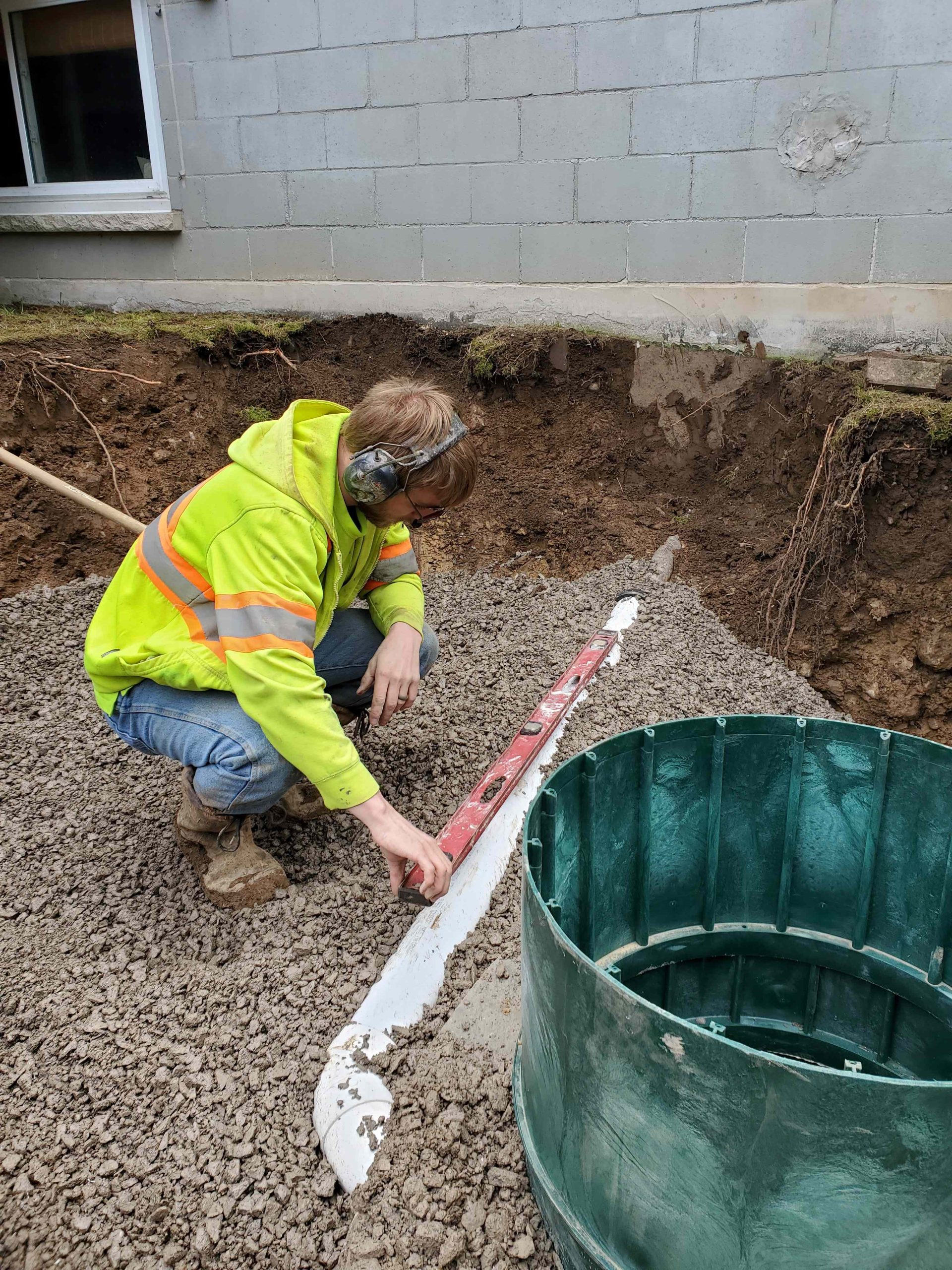 Alpha Ex crew installing septic tank risers and verifying slope alignment in Haldimand