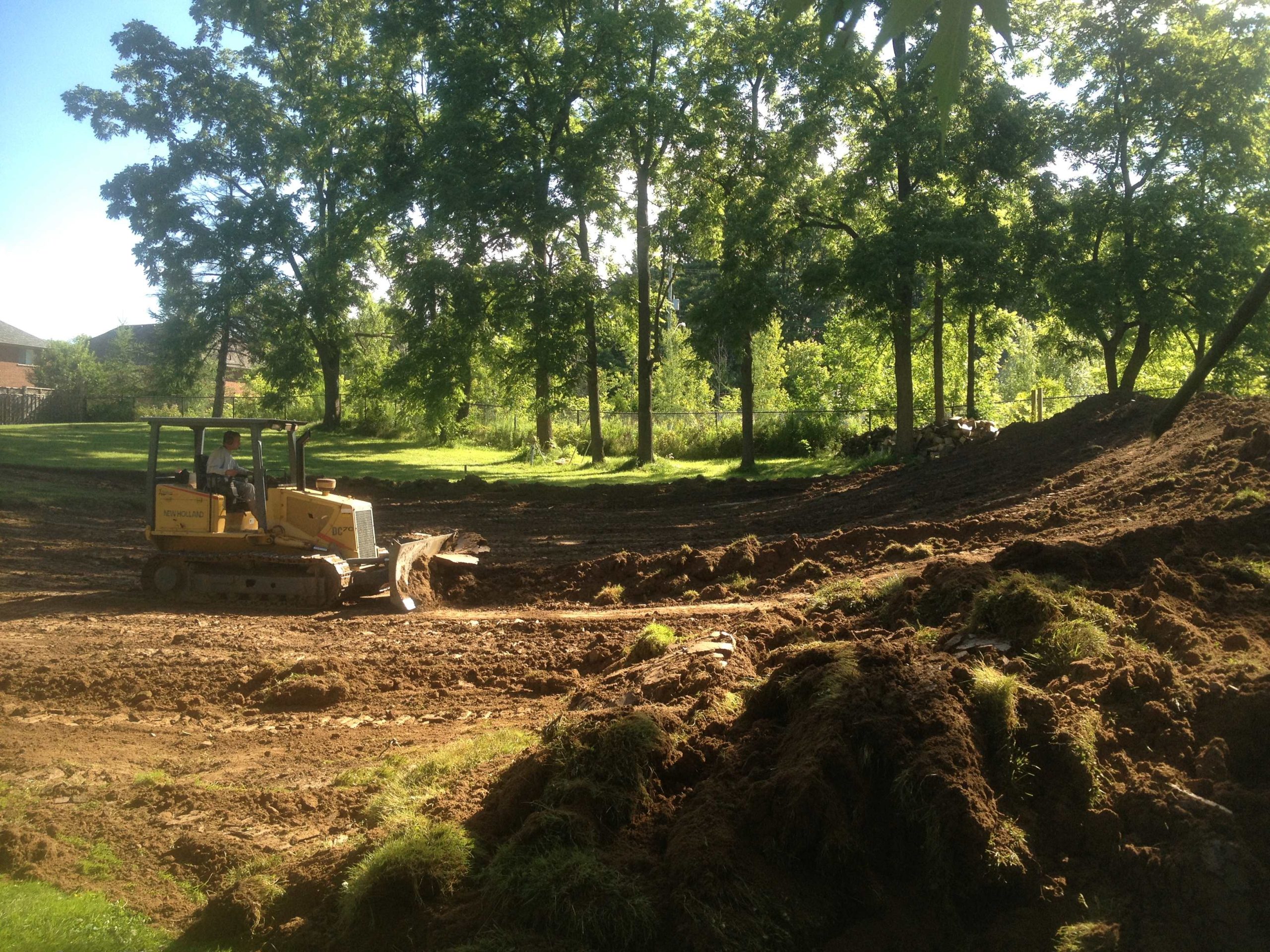 Removing topsoil to prepare for filter bed septic system installation in Ancaster, Ontario