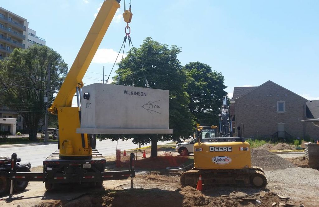 Crane placing a precast stormwater interceptor in Burlington