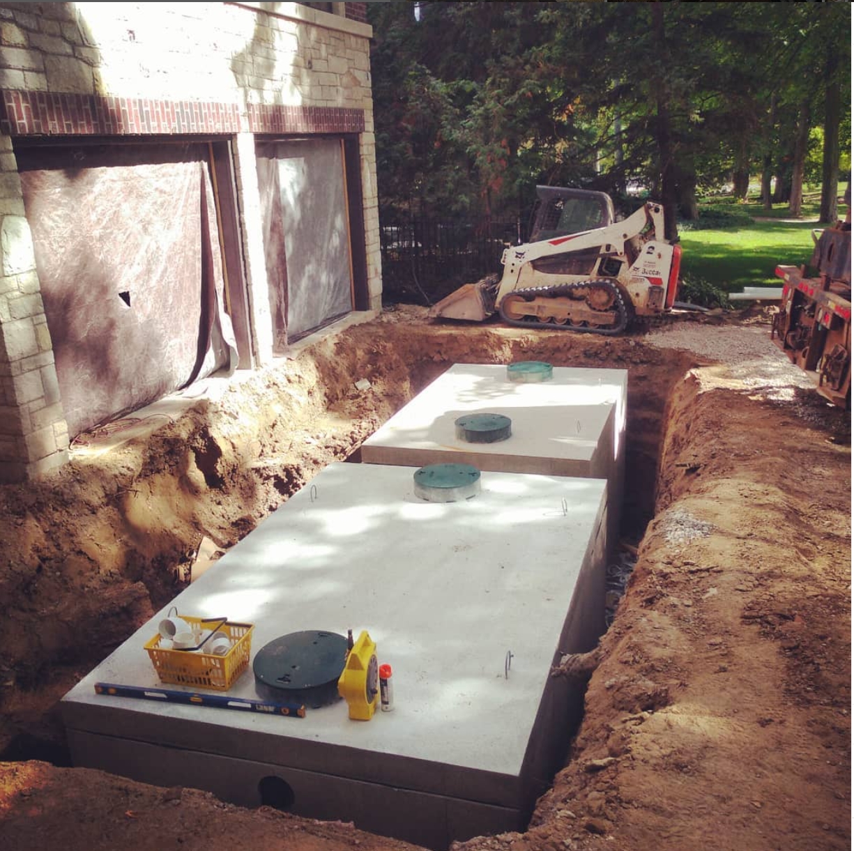 Traffic-rated septic tank and pump chamber installation under a driveway in Burlington, Ontario