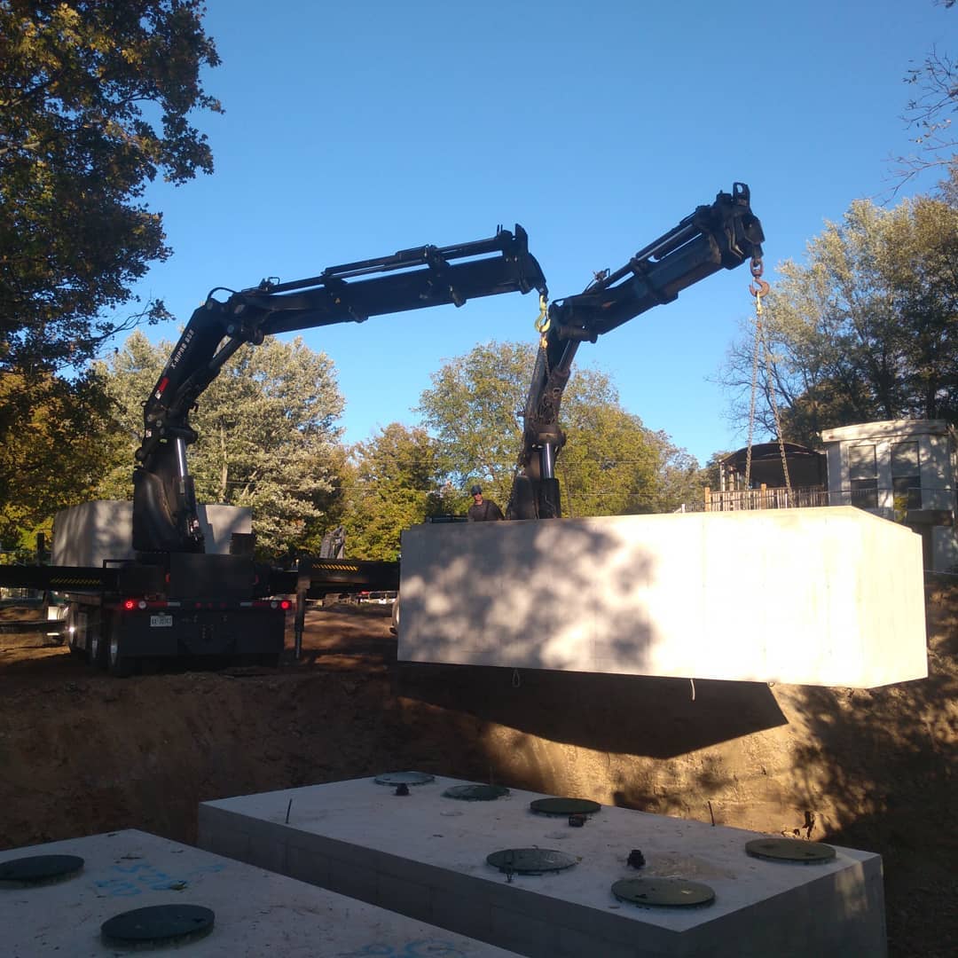 Two cranes lifting and positioning a septic tank in Haldimand with precision and safety.