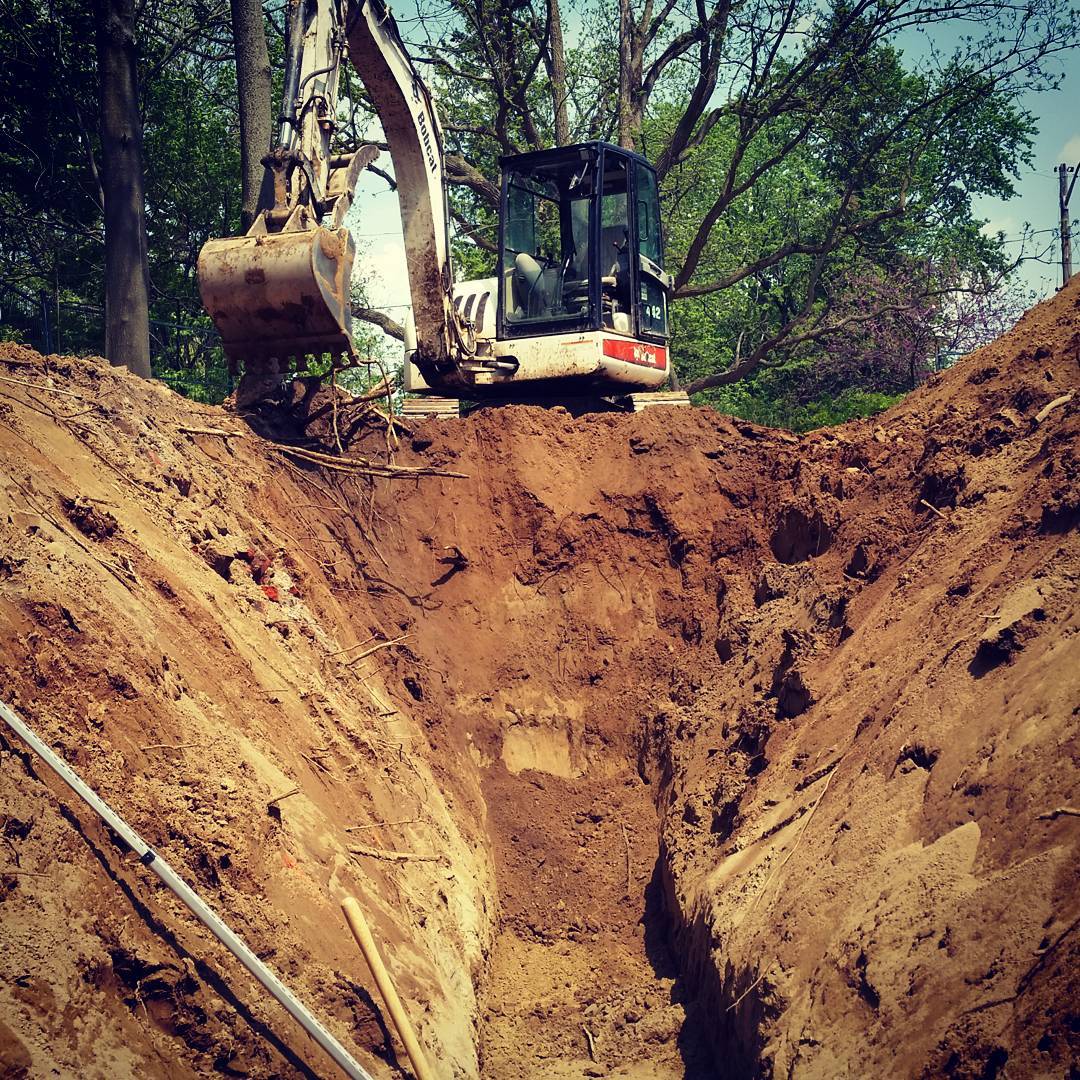 Trench banks sloped for safety during septic or sewer pipe installation